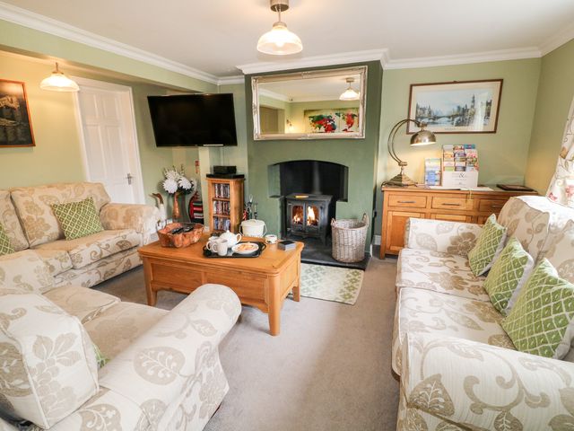 A living room with sofas a coffee table a wood burning stove and a wall mounted television at Aditum Cottage in East Barkwith near Wragby