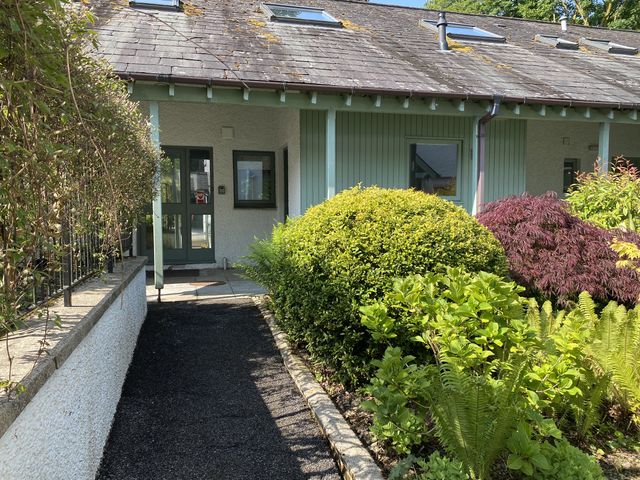 A pathway leading to a building surrounded by greenery at Beech - Woodland Cottages in Bowness-on-Windermere