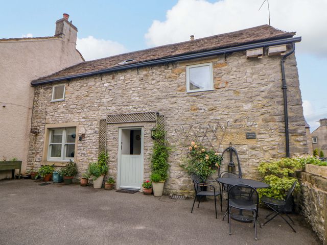 A stone house with an entrance door and seating area at Brookside Barn Bradwell