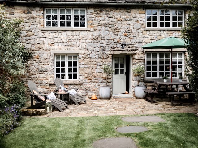 An outdoor space with chairs and a table near the stone wall at Bridge End Cottage Stainforth
