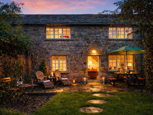 A house with a garden and patio furniture at Bridge End Cottage Stainforth