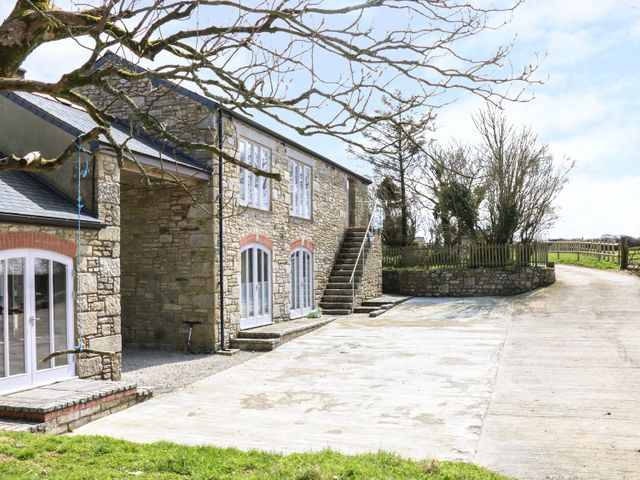 A stone building with multiple white doors and windows near a concrete driveway and leafless trees at Dexter in Treverva near Constantine