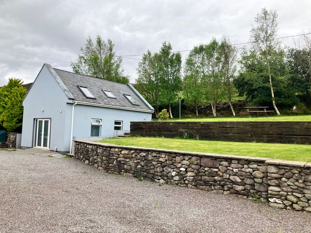 A house with a stone wall and grassy area at Silver Birch House Beaufort Killarney County Kerry