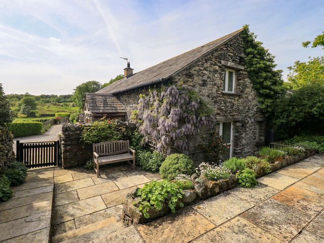 A stone cottage with a bench and garden at Pheasant Cottage in Beckside near Cartmel