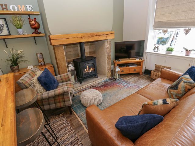 A living room with a fireplace, television, and sofa at Maria Cottage in Haworth