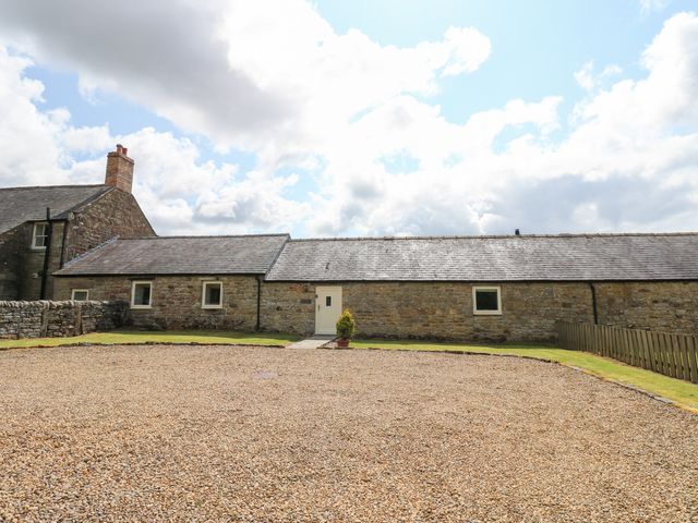 A stone cottage with a gravel driveway and a small plant at Shepherds Burn Cottage Bellingham
