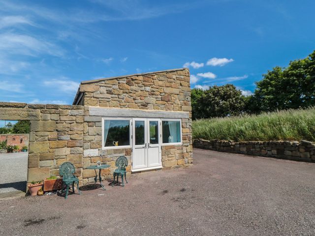 An outdoor seating area with stone walls and chairs at Field Cottage in Staithes