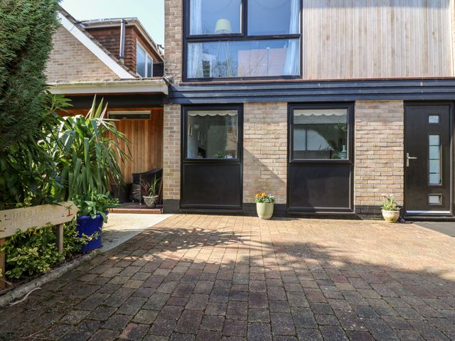A brick house with black framed windows and door with potted plants outside and a driveway at Little Beach House in Carlyon Bay