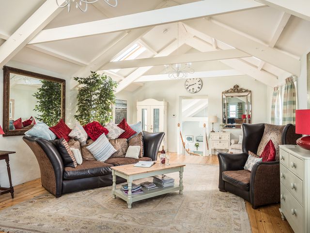 A living room with sofa chair coffee table and large mirrors at The Barn at Little Resugga Rescorla near St Austell