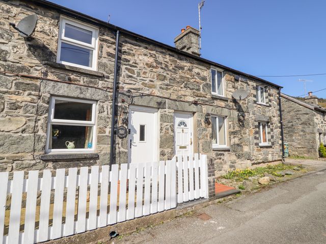 A stone exterior house with white windows doors and a white picket fence at 2 White Street in Penmachno