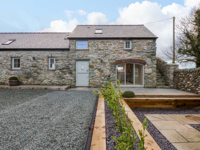 An outdoor area with a stone wall and gravel pathway at Storws Tanrallt