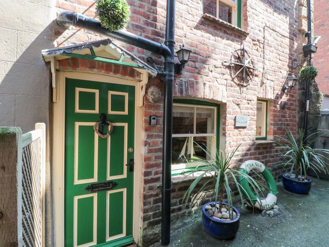 An outdoor area featuring a green door and brick wall at The Old Cottage in Staithes