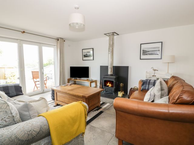 A living room with two sofas a wooden coffee table a wood stove and a TV at 54 The Moorings in St Dogmaels