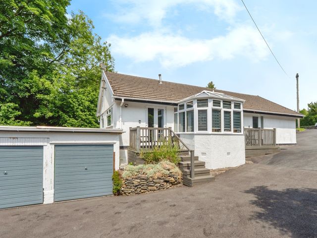 An exterior view of a house with a conservatory and garage at Mylnebeck Lodge Bowness-on-Windermere