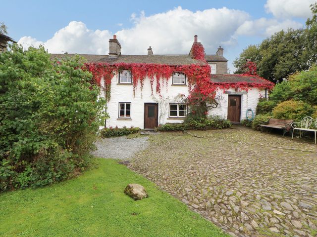 A house with ivy on the wall and a path in the garden at Mill Cottage in Garnett Bridge
