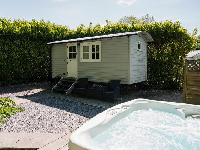 A hot tub and a cabin in a garden area at The Snug in Longtown