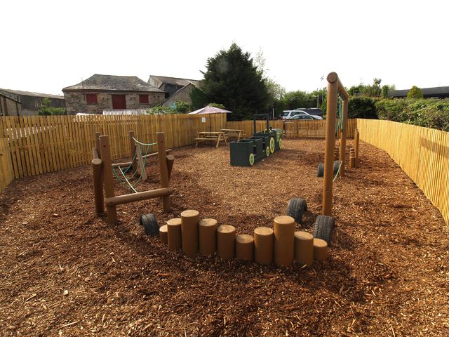 An outdoor play area with swings and climbing frame at Maple Lodge in Lanivet near Bodmin