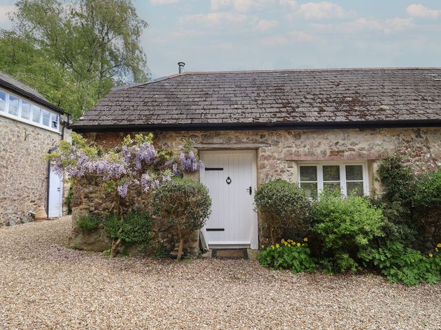An exterior view of a cottage with a white door and plants at Pottery Barn in Branscombe