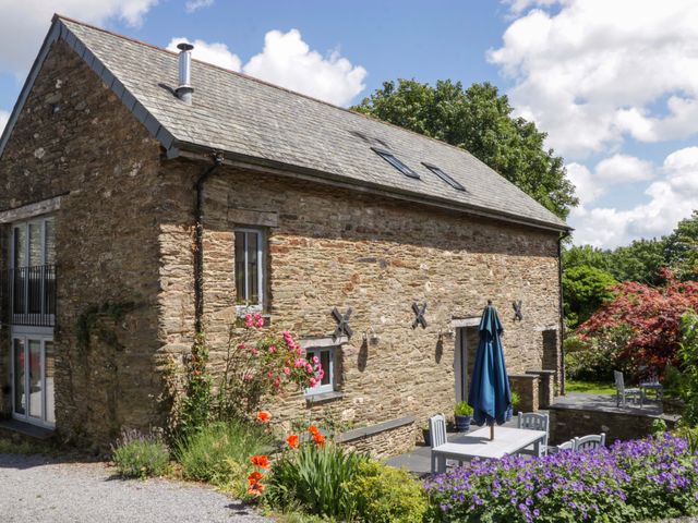An outdoor area with a building, table, chairs, and plants at The Hay Barn in Halwell