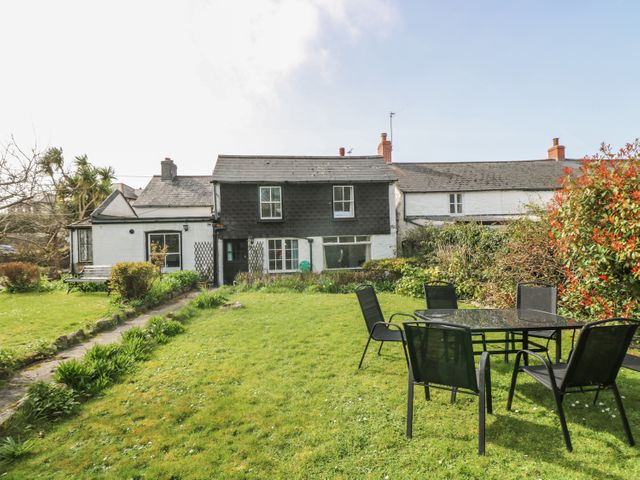 A garden with grass and outdoor table and chairs in front of a house with white and dark siding at Boundys House in St Ives