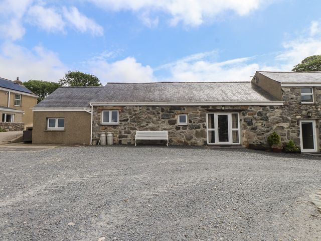 An outdoor area with a stone building and a bench at Coetsiws in Clynnog Fawr