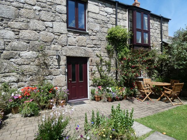An outdoor area with table and chairs by stone wall at Brunnion House in St Ives