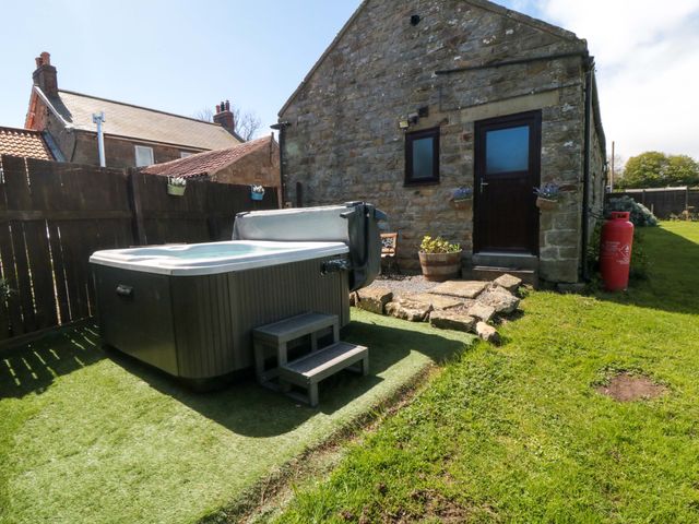 A garden with a hot tub and a building at Carters in Staintondale near Burniston