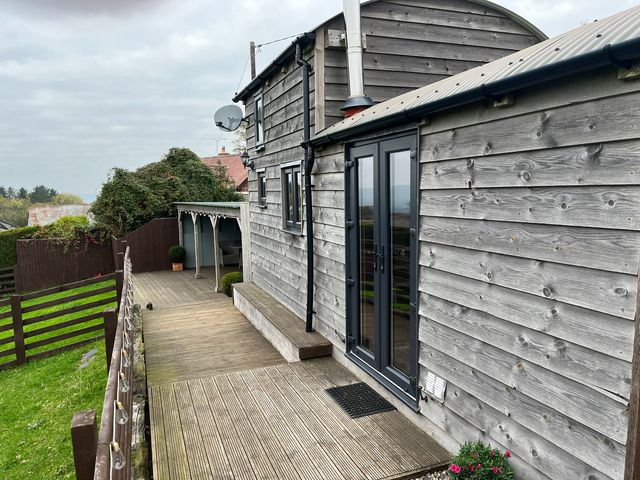 A wooden building with decking and garden area at Shepherds Cabin at Titterstone Clee Hill