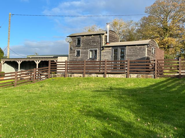 A cabin with a fence and grass at Shepherds Cabin at Titterstone in Clee Hill
