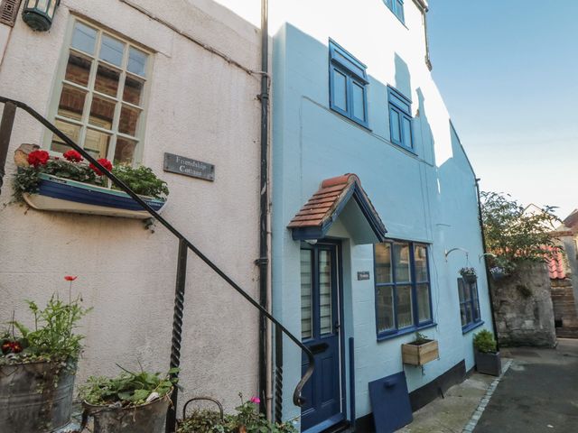 A blue and white house with flower planters at Friendship Cottage in Staithes