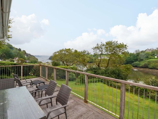 An outdoor area with a table and chairs overlooking a river at The Meadow in Feock near Carnon Downs