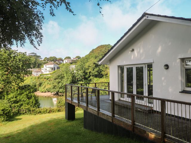 A house with a deck overlooking water and trees at The Meadow in Feock near Carnon Downs