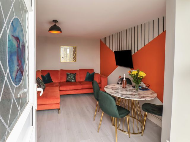 A living room with orange sofa green chairs and a round marble dining table at Apt 2 Hunter's Quay in Bridlington