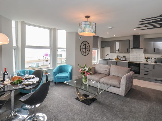An open plan living room and kitchen with a grey sofa and glass coffee table at Apt 5 @ Hunter's Quay in Bridlington