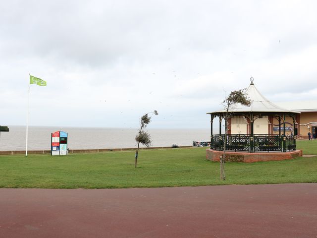 A grassy area near a body of water with a gazebo and a flagpole at Tilly's Retreat in Hunstanton