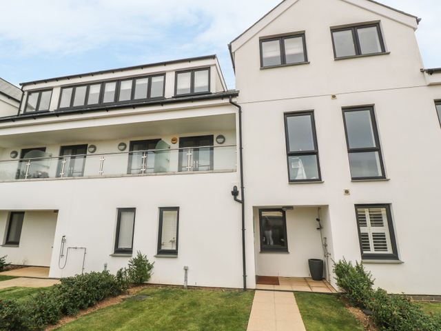 A modern white residential building with multiple windows and a glass balcony at Seaspell Beach House in Constantine Bay
