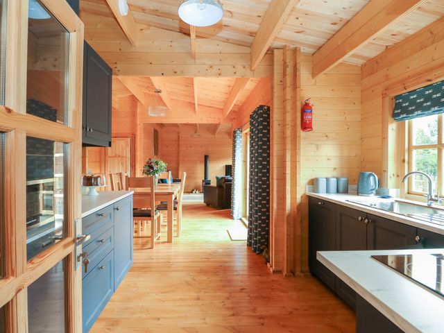 A kitchen and dining area with wooden walls and ceiling and blue cabinets at Tythe Lodge in Howell near Heckington