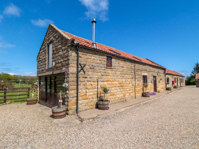 An outdoor view of a stone building with a pathway at Stable Cottage in Staintondale near Burniston