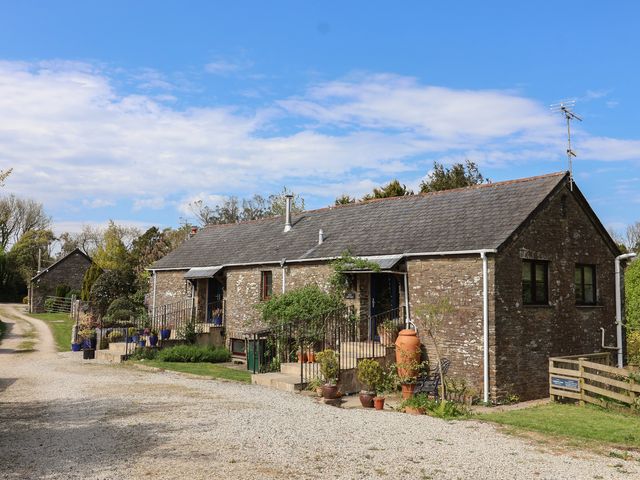 A stone building with plants and gravel path at Lily Cottage in Looe