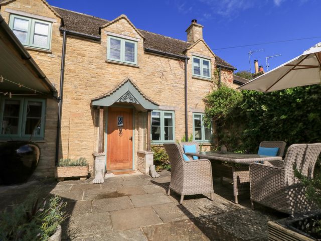 A stone house with a patio and outdoor furniture at Fairview Cottage in Milton-Under-Wychwood