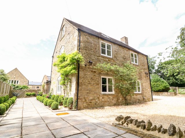 Stone house with paved pathway and neatly trimmed bushes at South Hill Farmhouse Stow-On-The-Wold