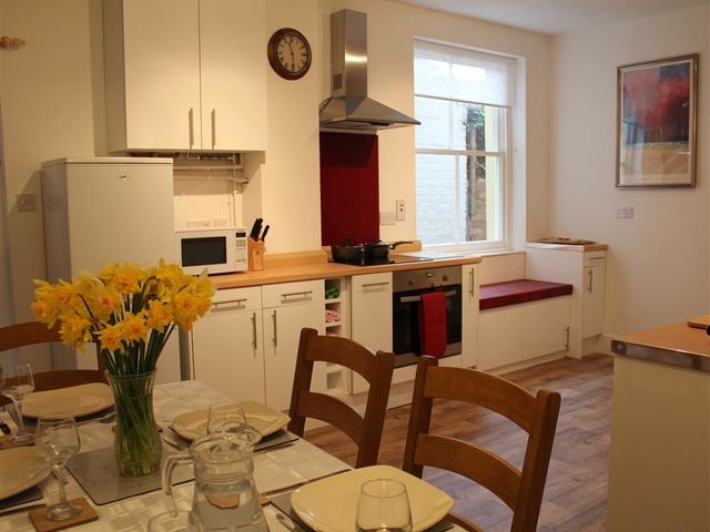 A kitchen with white cabinets and wooden countertops with a dining table set with plates and glasses at Rojoy in Salisbury