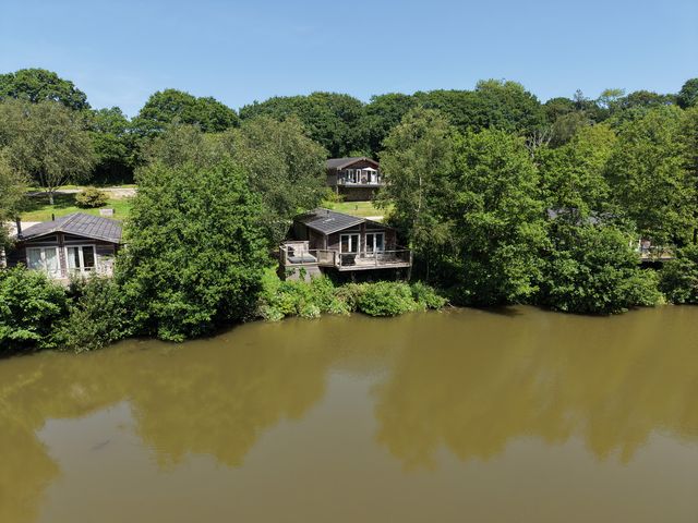 An outdoor area with cabins near a lake at 4 Water's Edge in Lanreath