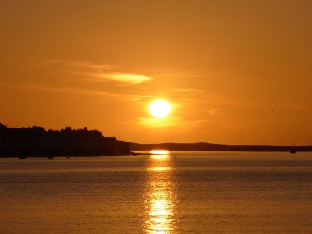 A sunset over water with a silhouette of buildings on the left at Beach Retreat in Instow