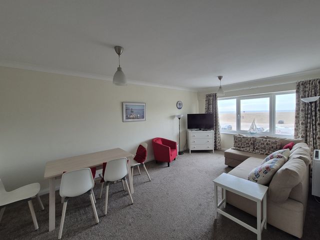 A living room with a sofa and dining area at Jurassic View West Bay