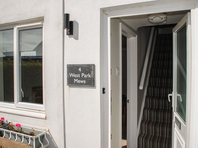 A house entrance with open door showing a striped carpeted staircase and a window with a flower box at 4 West Park Mews Hope Cove