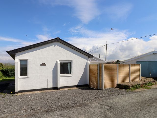 A house with a wooden fence and gravel pathway at Maes Y Coed in Morfa Nefyn