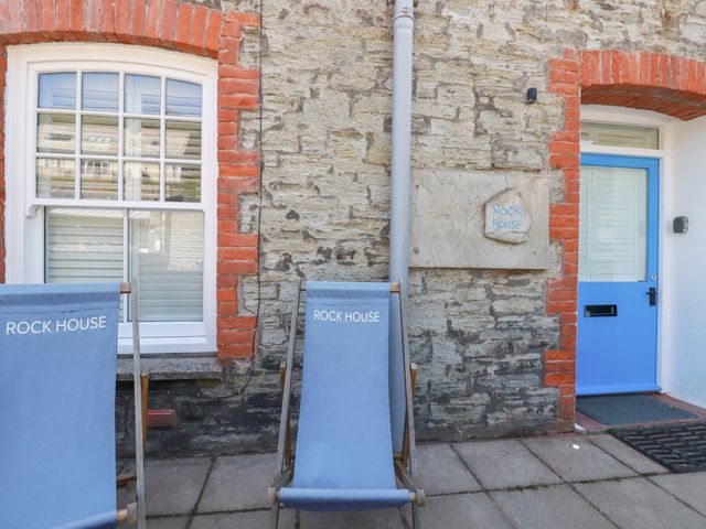 An outdoor area with deck chairs and a blue door at Rock House in Trebarwith Strand near Tintagel