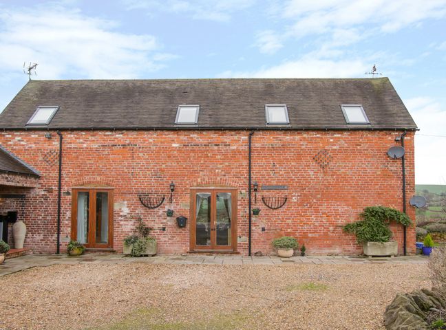 A brick building with skylights and wooden doors with plants outside at Southdown in Much Wenlock