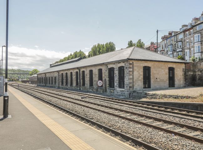 Railway platform with tracks and a long stone building beside it at Mallard @ Engine Shed in Whitby